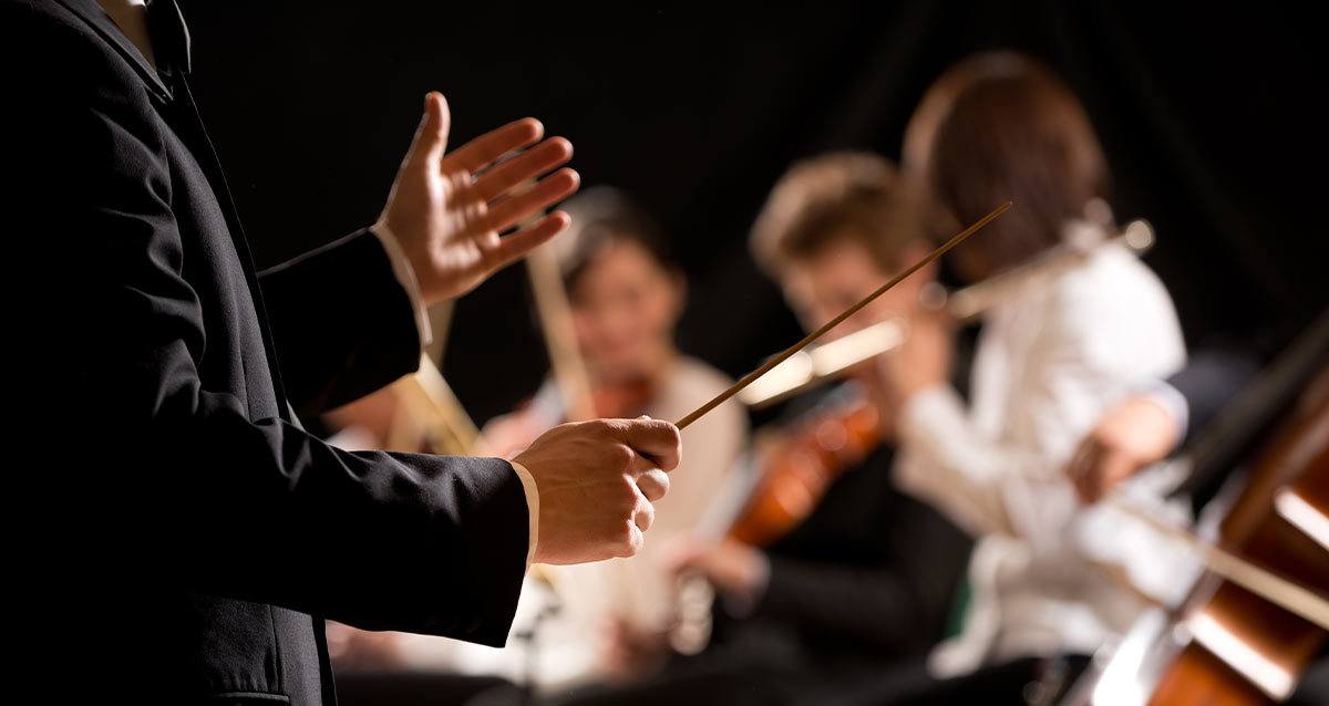 a side view of a conductor leading an orchestra